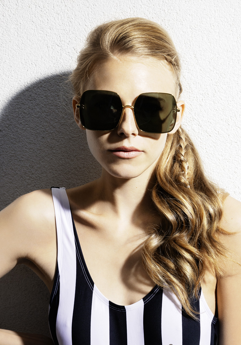 Model Portrait im schwarz weissen Badeanzug präsentiert eine Sonnenbrille